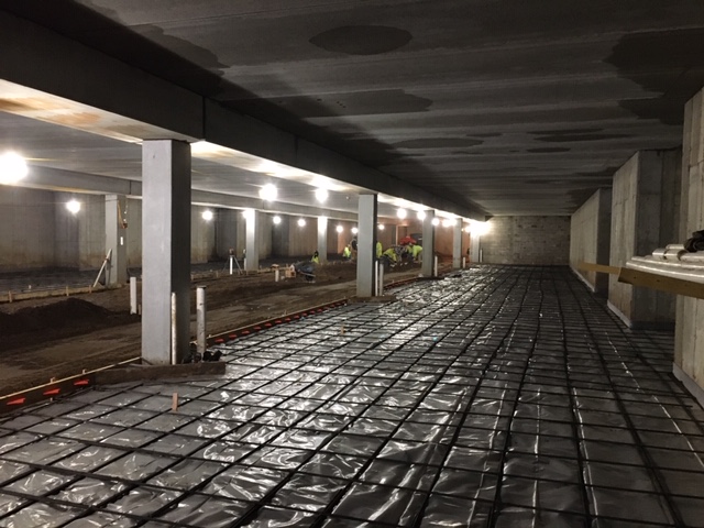 Underground parking under construction with rebar, concrete columns, and slab
